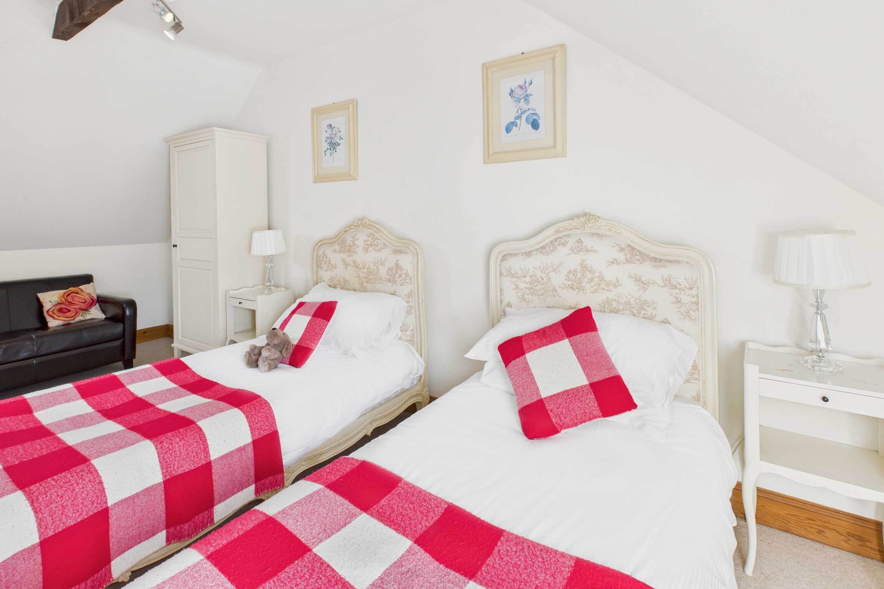 Quarto com duas camas, um guarda-roupa, uma mesa de cabeceira e um abajur.