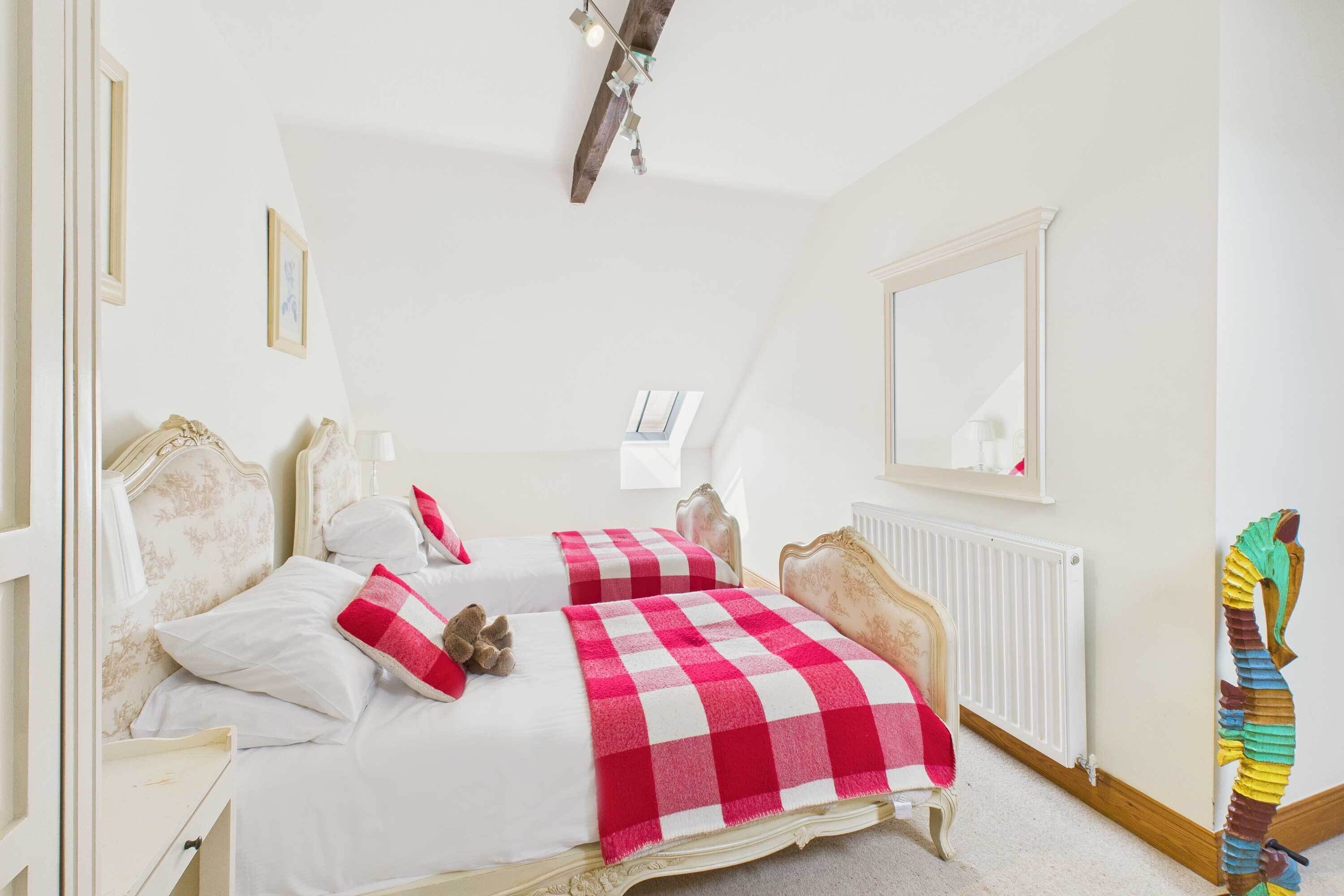 A bedroom with two beds, a radiator, a mirror, and a colorful sculpture.