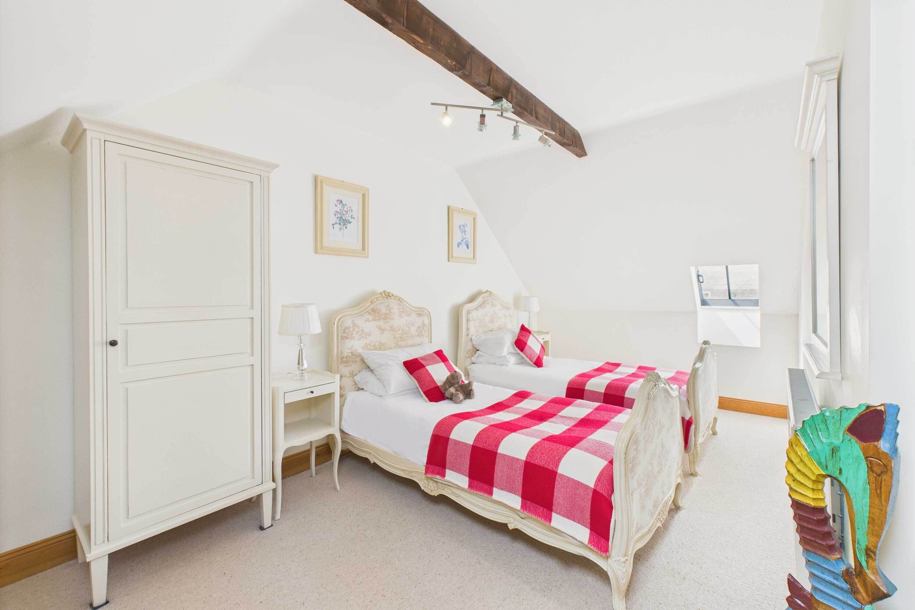 Een slaapkamer met twee bedden, een kledingkast en een nachtkastje.