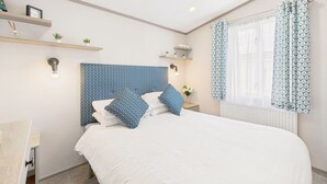 Ein Schlafzimmer mit einem großen Bett, einem Kopfteil mit blauem Muster, Nachttischen mit Lampen und einem Fenster mit gemusterten Vorhängen.