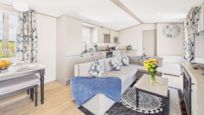 Ein modernes Wohnzimmer mit einer Couch, einem Couchtisch und einem Essbereich mit Tisch für zwei Personen.