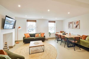 A modern living room with a sofa, coffee table, and dining area.