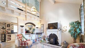 A spacious living room with a fireplace, a television, and a kitchen area visible through an archway. - Host Stay The Cheeky Squirrel (Wallasey)