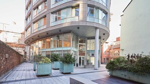 A modern building with a curved facade, large windows, and outdoor seating areas with planters. - Host Stay 608 Hatton Garden (Liverpool)