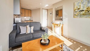 A modern living room with a grey sofa, a wooden coffee table with a plant, and a kitchen in the background. - Host Stay 608 Hatton Garden (Liverpool)