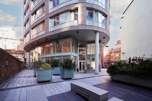 A modern building with a curved facade, large windows, and a covered entrance. There are planters with greenery in front. - Host Stay 207 Hatton Garden (Liverpool)
