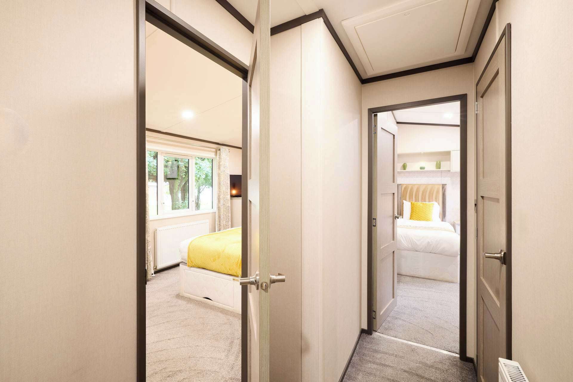A hotel room with a bed, a window, and a door leading to another room.