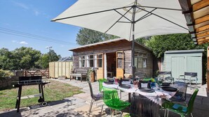 An outdoor patio with a table set for dining, surrounded by chairs, and a barbecue grill. - Host Stay Windles (Wotton-under-Edge)