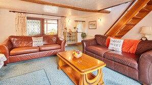 A cozy living room with two brown leather sofas, a wooden coffee table, and a blue patterned carpet. - Host Stay Windles (Wotton-under-Edge)