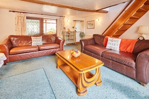 A cozy living room with two brown leather sofas, a wooden coffee table, and a blue patterned carpet. - Host Stay Windles (Wotton-under-Edge)