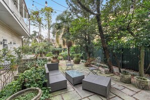 Eine Terrasse mit Korbmöbeln, Topfpflanzen und einem Steinweg.