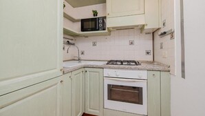 Uma cozinha compacta com micro-ondas, fogão, forno e pia.