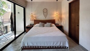 A bedroom with a large bed, two bedside tables, a ceiling fan, and two hanging lamps. - Jungle  Studio Balcony & Hammock S19 (Tulum)