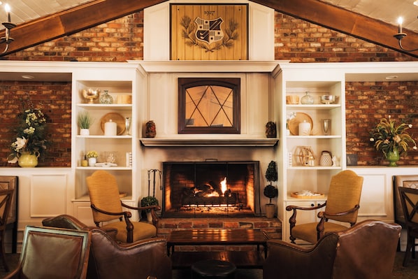 A cozy living room with a fireplace, wooden shelves, and leather chairs.