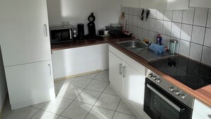 A modern kitchen with white cabinets, a black stove, and a stainless steel sink. - Stylish time out in the Hunsrück - views and comfort (Herrstein)