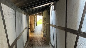 A narrow corridor with stone flooring and wooden beams, leading to a brighter area. - Stylish time out in the Hunsrück - views and comfort (Herrstein)