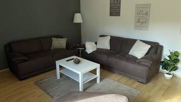 A modern living room with two sofas, a white coffee table, and a grey ottoman.