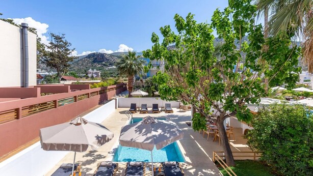 Uma área de piscina no terraço com espreguiçadeiras, guarda-sóis e vista para a paisagem ao redor.