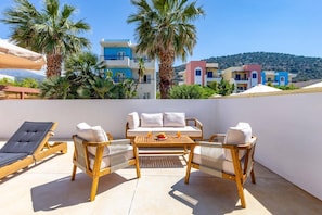 A terrace with a table, chairs, and a lounge chair. - Villa Suntouch by Villa Plus (Malia)
