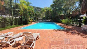 Une piscine avec des chaises longues et une terrasse en briques.