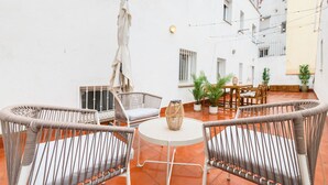 A patio with wicker furniture, a round table, and potted plants. - Modern 2-bedroom flat with terrace and fully equipped kitchen_ Madrid . MAL71A (Madrid)