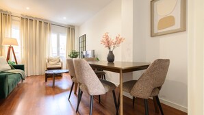 A modern living room with a dining area, featuring a wooden floor, a sofa, a coffee table, and a dining table with four chairs. - Modern 2-bedroom flat with terrace and fully equipped kitchen_ Madrid . MAL71A (Madrid)
