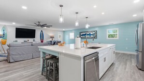 A modern kitchen with a central island, white cabinetry, and stainless steel appliances. - 8BR Luxe Retreat w/ Pool, Spa & Rooftop Deck, Beach + Bay Views, Walk to Beach (Bradenton Beach)