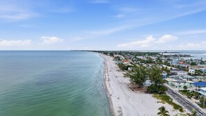 A coastal town with a beach, houses, and a road. - 8BR Luxe Retreat w/ Pool, Spa & Rooftop Deck, Beach + Bay Views, Walk to Beach (Bradenton Beach)