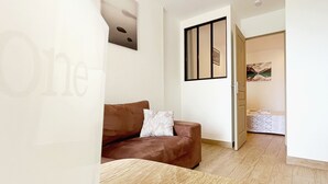 Ein modernes Wohnzimmer mit einem braunen Sofa, einem Holztisch und einer weißen Wand mit einem gerahmten Bild.