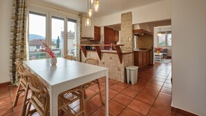A kitchen with a dining area, large windows, and a view of the outside.