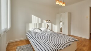 A bedroom with a bed, a wardrobe, and a mirror.
