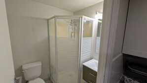 Een badkamer met een douchecabine van glas, een toilet en een wastafel met spiegel.