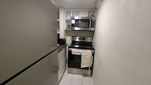 Een kleine keuken met een magnetron, oven en broodrooster.