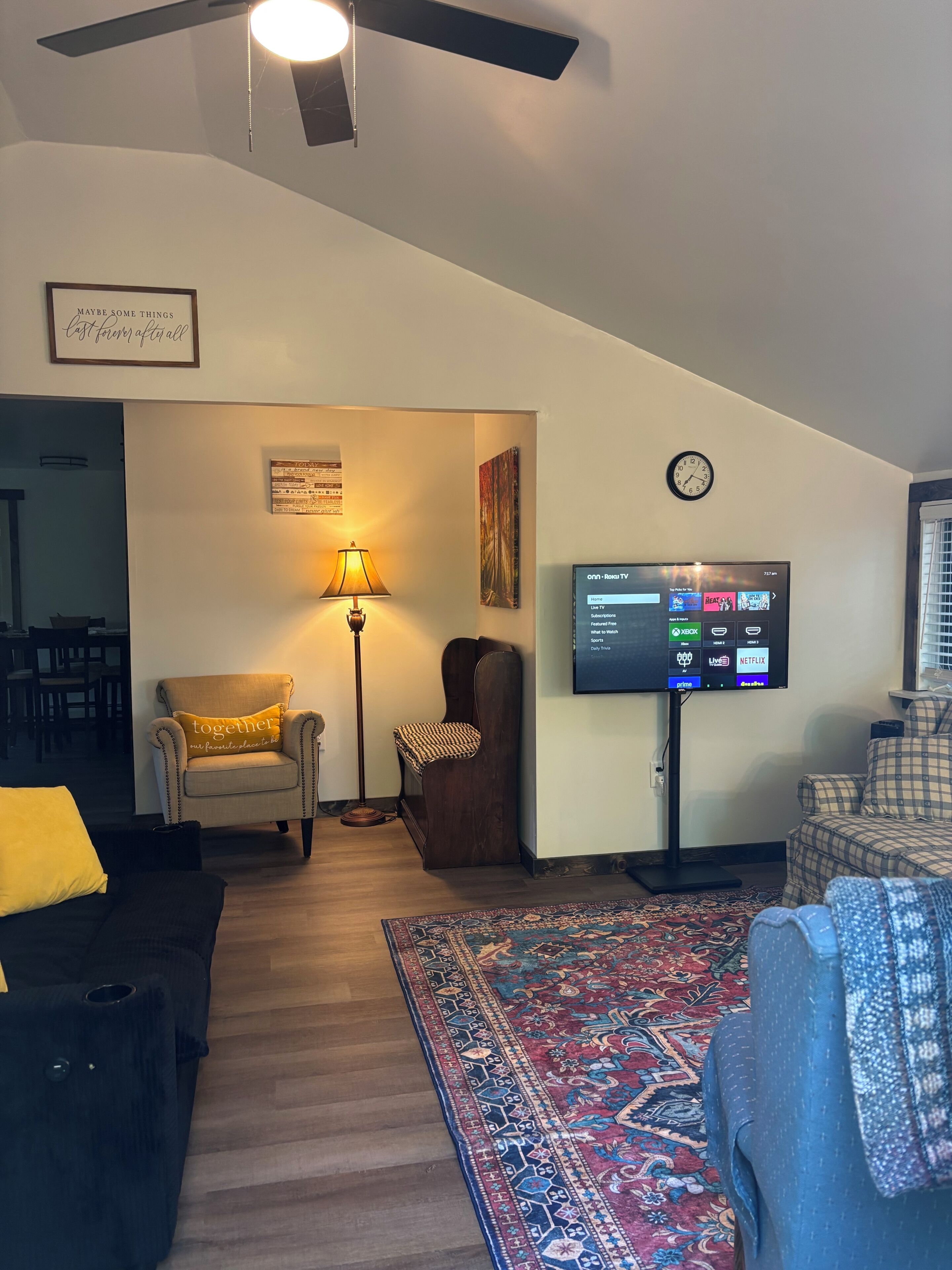A living room with a TV, a lamp, a clock, and a sofa.