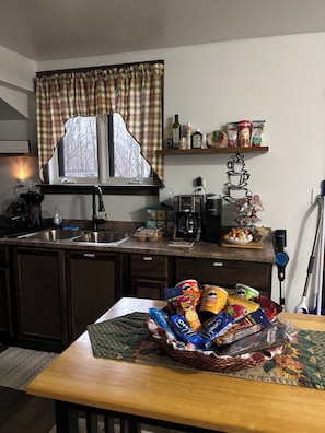 A kitchen with a window, a coffee maker, and various food items on the counter.