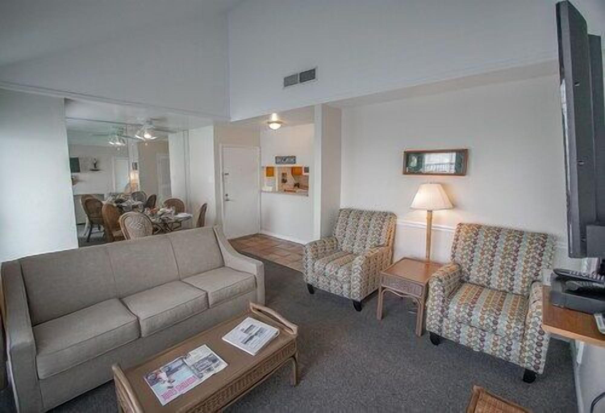 A living room with a sofa, two armchairs, a coffee table, and a television.