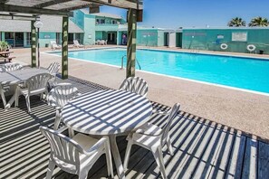 A pool area with a covered deck, lounge chairs, and a poolside table. - 2BR Stay w/ Bay Views | Near Beach + Pool & Dock (Corpus Christi)