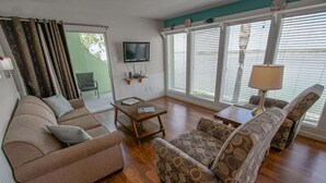 A living room with a sofa, a coffee table, and a TV. - Near the Beach 3BR Stay | Poolside BBQ + Fishing (Corpus Christi)