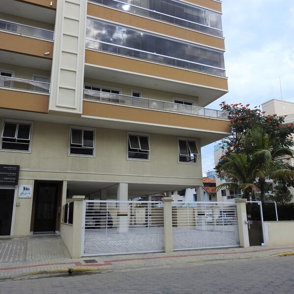 Un edificio de varios pisos con fachada plana, balcones y una entrada protegida por una reja.