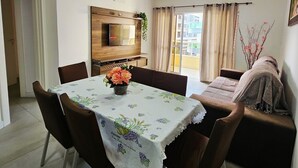 Un coin repas avec une table dressée pour quatre personnes, un canapé et un téléviseur fixé au mur.