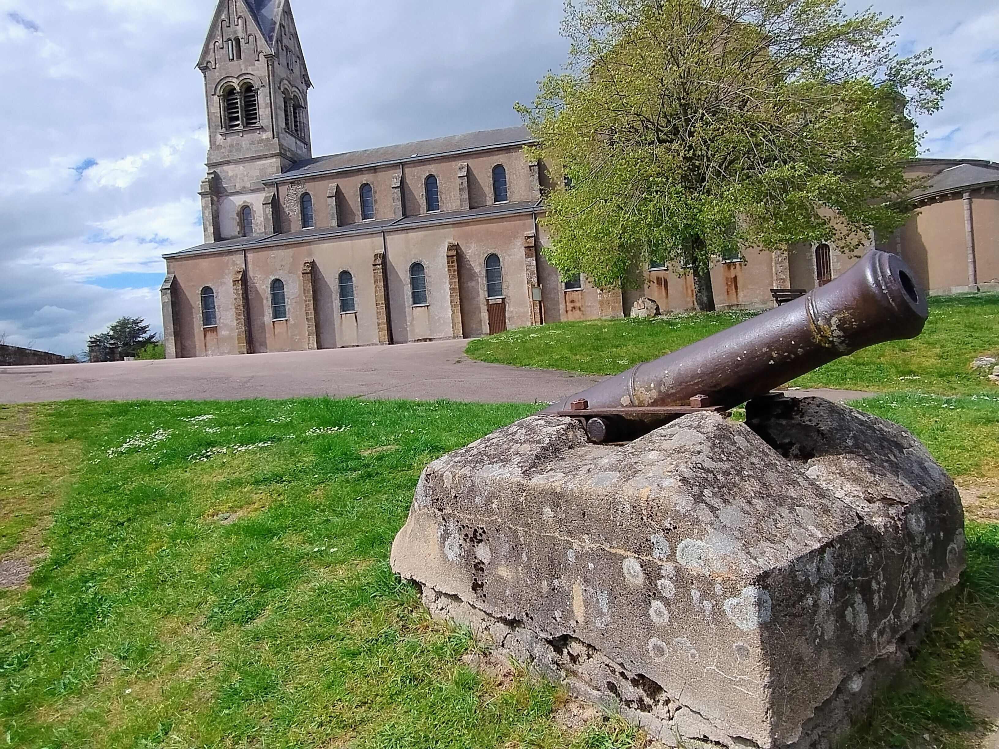 A historical building with a prominent tower and a cannon on a stone base.