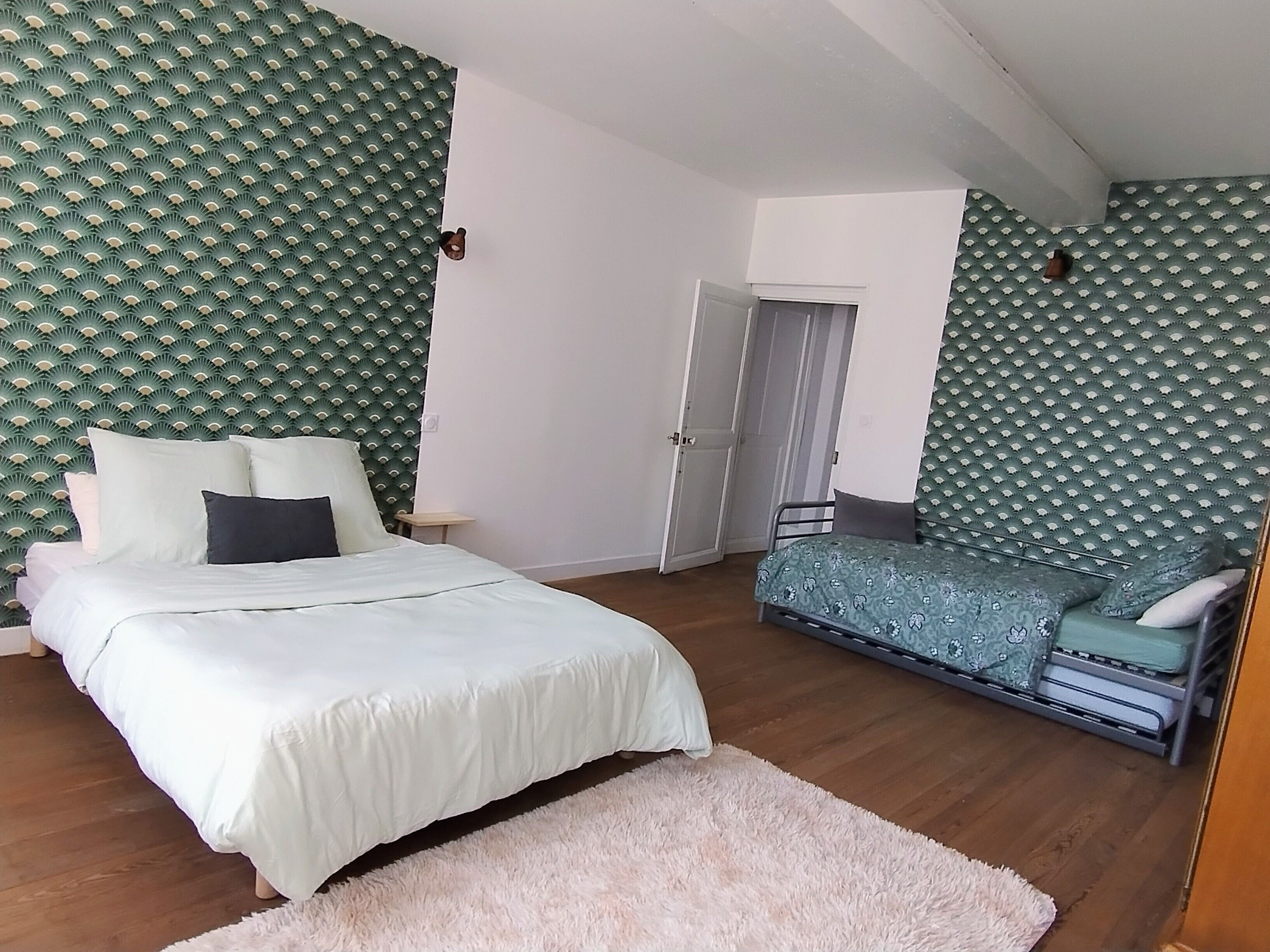 Ein Schlafzimmer mit einem Bett, einem Sofa, einer Tür und einer Wand mit Muster.