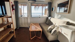 Une pièce avec une table en bois, un canapé avec des coussins, une télévision et une fenêtre donnant sur la mer.