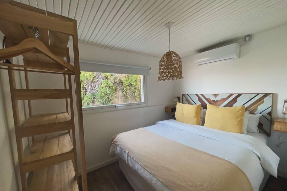Un dormitorio con cama, muebles de madera, una ventana y una lámpara colgante.