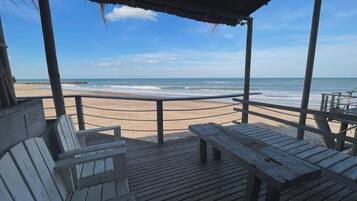 Terraza de madera con bancos que da a una playa.