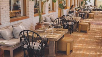 An outdoor seating area with brick flooring, tables, chairs, and hanging planters.