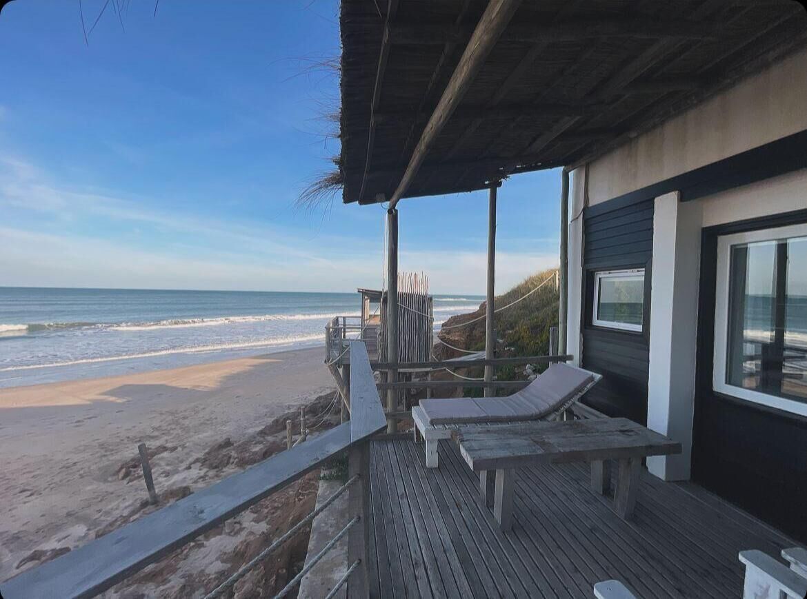 A beachside wooden deck with lounge chairs, overlooking the ocean.