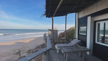 A beachside wooden deck with lounge chairs, overlooking the ocean.