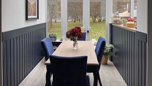 A conservatory with a table and chairs, a vase of flowers, and a view of the garden. - Cottage 492 - Clifden - sleeps 5 guests  in 3 bedrooms (Clifden)