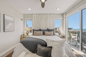 A bedroom with a large bed, a view of the sea, and a balcony with chairs. - Oceanside paradise, 1 block from beach. Amazing rooftop, 3bd/3.5 bath (Oceanside)